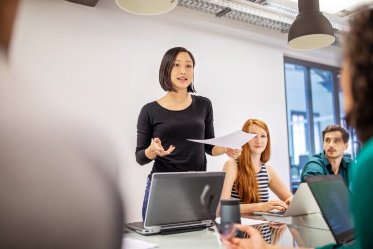 Confident female professional discussing in board room. Group of business colleagues planning together in meeting.