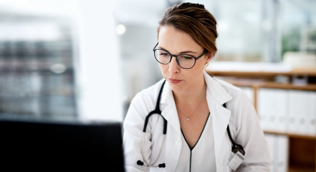 Cropped shot of a female doctor working on a computer in her office at the hospital doing a software upgrade compliance for  HIPAA protected personal health information (PHI).