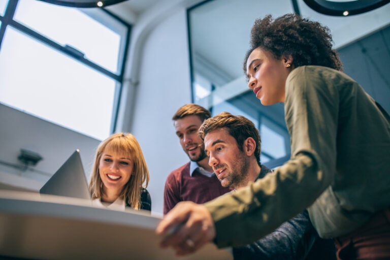 Team of business professionals in an office using a laptop device to check on Office 365 outsourcing features.