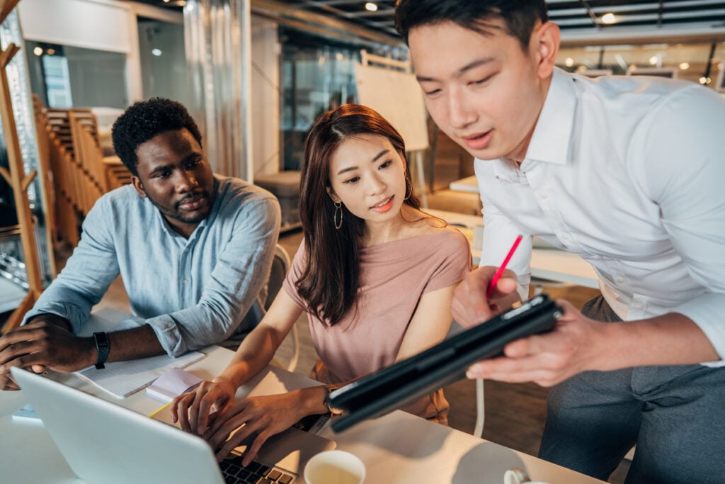 Manufacturing firm professionals in an office using a laptop with Azure DevOps tools to manage their business.