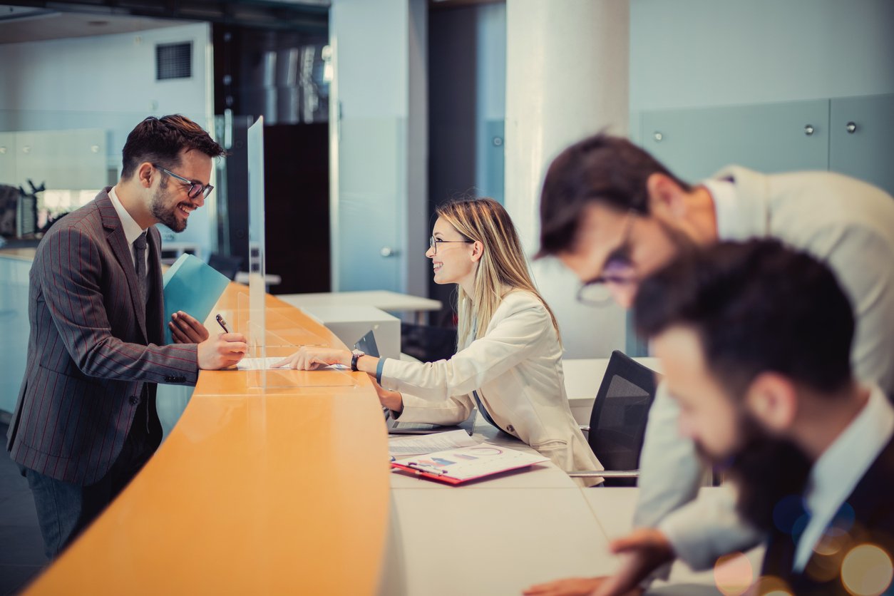 A photo of bank employees and a customer happily signing a document at the bank counter