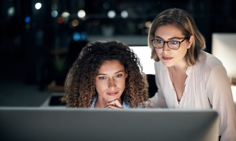 Professionals looking at a computer while working in an office to suggest managed IT services cost.