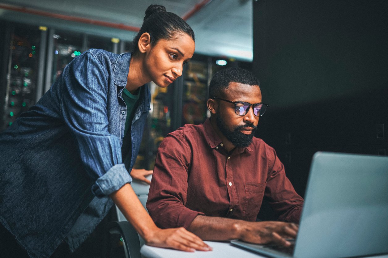 IT professionals in a server room using a laptop - working with managed IT services provider.