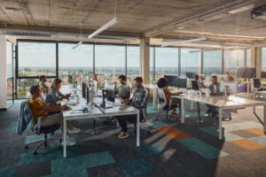 Proper IT lifecycle management - Group of employees in an office working on their own computers to accomplish tasks.