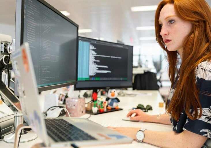 woman in green shirt sitting in front of computer